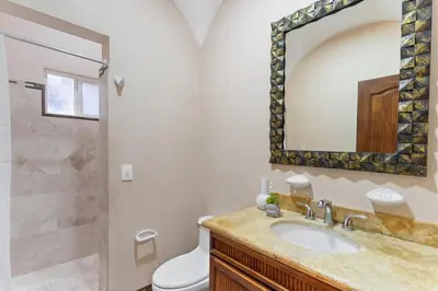 a bathroom with a sink and a toilet and a mirror at HM103 Blissful 2BR Beachfront Condo in Tamarindo