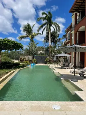 a swimming pool in a resort with palm trees at HM103 Blissful 2BR Beachfront Condo in Tamarindo