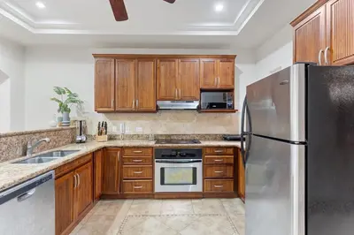 a kitchen with wooden cabinets and a stainless steel refrigerator at HM103 Blissful 2BR Beachfront Condo in Tamarindo