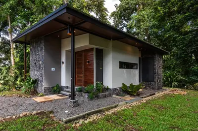 a small house with a wooden door in a yard at Río Sarapiquí Lodge in Sarapiquí