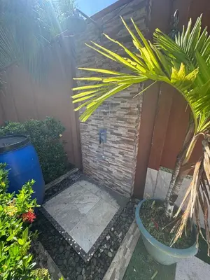 a garden with a palm tree and a brick wall at Alma y Paz Beach House in Bejuco