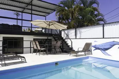 a swimming pool with a table and chairs and an umbrella at JS -14B home in Jacó