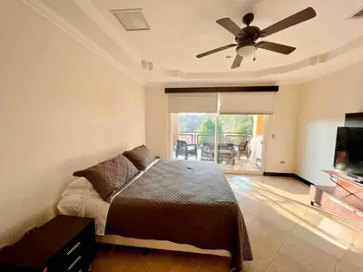 a bedroom with a bed and a ceiling fan at Pacific Sun Penthouse in Herradura