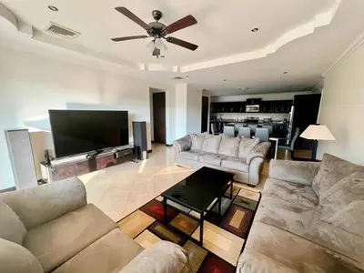 a living room with couches and a flat screen tv at Pacific Sun Penthouse in Herradura