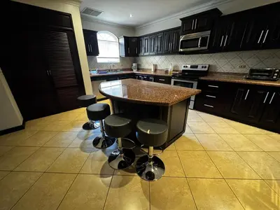 a kitchen with a island with bar stools at Pacific Sun Penthouse in Herradura