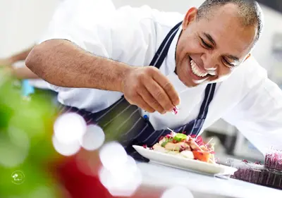 a man in a kitchen preparing a plate of food at Monaco Condominiums Unit 3, Poolside 3BR, Walk to Beach in Jacó
