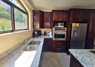 a kitchen with stainless steel appliances and wooden cabinets at Monaco Condominiums Unit 3, Poolside 3BR, Walk to Beach in Jacó