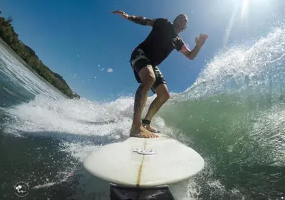a man riding a wave on a surfboard in the ocean at Monaco Condominiums Unit 3, Poolside 3BR, Walk to Beach in Jacó