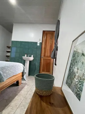 a bedroom with a bed and a bathroom with a sink at Casa Los Delfines in Tortuguero