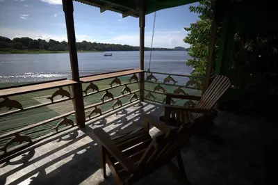 a porch with a chair and a view of the water at Casa Los Delfines in Tortuguero
