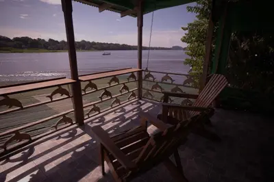 a group of birds sitting on a porch overlooking the water at Casa Los Delfines in Tortuguero