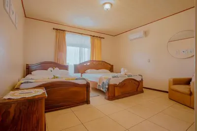a bedroom with two beds and a chair and a window at Casa vacacional cerca de la Fortuna San Carlos in Tanque