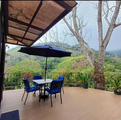 a table and chairs with an umbrella on a deck at Cabaña Lotf Atenas in San Isidro