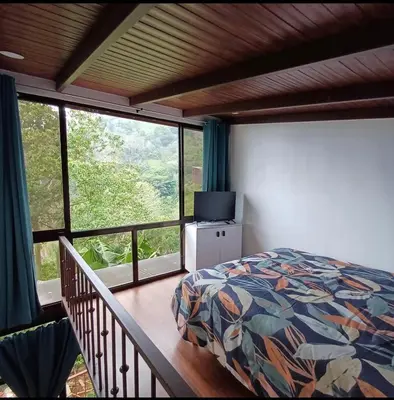 a bedroom with a bed and a large window at Cabaña Lotf Atenas in San Isidro