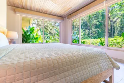 a bedroom with a large bed and large windows at Chalet Tropical - by Pura Villas in Ballena