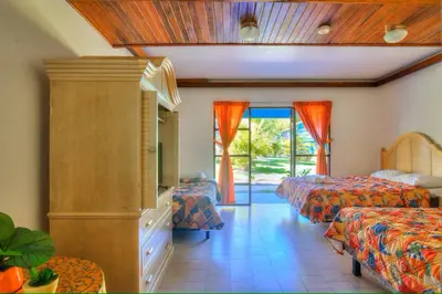 a bedroom with two beds and a tv and a window at Beach Break Resort & CR Surf Camp in Jacó