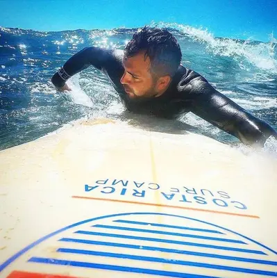 a man laying on a surfboard in the ocean at Beach Break Resort & CR Surf Camp in Jacó