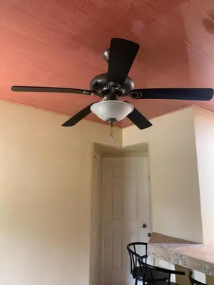 a ceiling fan in a room with a table at Hospedaje Oropendola Nest in Bagaces