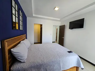 a bedroom with a bed with a blue wall at Apartamento Boulevar Park in Heredia