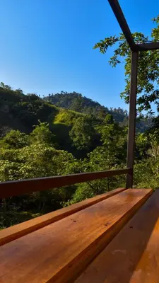 a wooden bench with a view of a mountain at Cabaña el Chapuzón montaña y rio, lugar fresco in Cedral