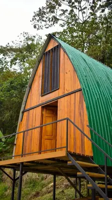 a small wooden house with a green roof at Cabaña el Chapuzón montaña y rio, lugar fresco in Cedral