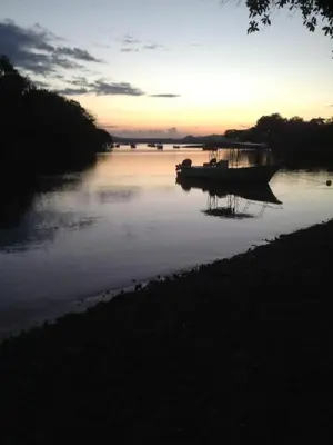 a boat is docked on a river at sunset at Casas Vacacionales Tambor Beach in Puntarenas