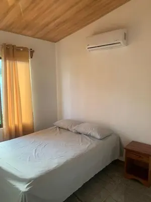 a bedroom with a bed and a air conditioner at Casas Vacacionales Tambor Beach in Puntarenas