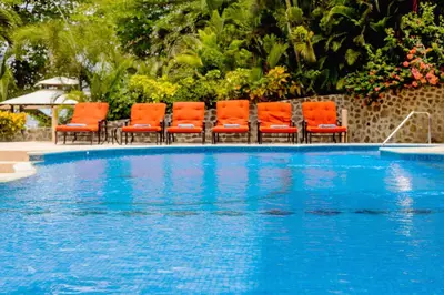a group of orange chairs next to a swimming pool at Ocean Front Palacio Tropical in Puntarenas