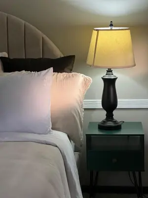 a lamp on a night stand next to a bed at Apartamento Chic en la Montaña AC in Turrialba