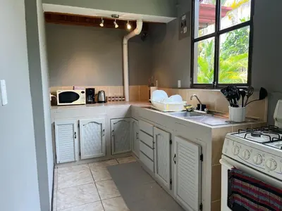 a kitchen with white cabinets and a sink and a stove at Apartamento Chic en la Montaña AC in Turrialba
