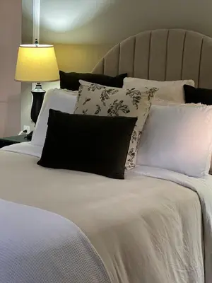 a bed with black and white pillows on it at Apartamento Chic en la Montaña AC in Turrialba