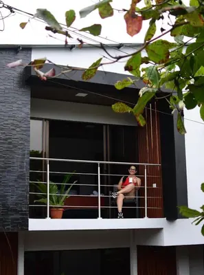 a woman sitting on a balcony of a building at Villa JADE, La Fortuna Downtown Apartment in Fortuna