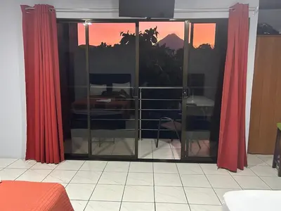 a room with sliding glass doors with red curtains at Villa JADE, La Fortuna Downtown Apartment in Fortuna
