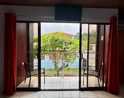 a room with a sliding glass door with a view of a tree at Villa JADE, La Fortuna Downtown Apartment in Fortuna