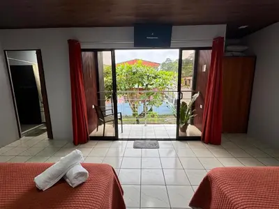 a bedroom with two beds and a view of a patio at Villa JADE, La Fortuna Downtown Apartment in Fortuna