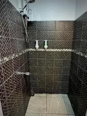 a bathroom with a shower with brown tiles at Villa JADE, La Fortuna Downtown Apartment in Fortuna