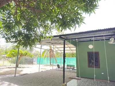 a green building with a swing in front of a beach at Casa Mangos Macondo Lepanto in Lepanto