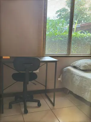 a desk with a chair next to a bed and a window at Casa Mangos Macondo Lepanto in Lepanto