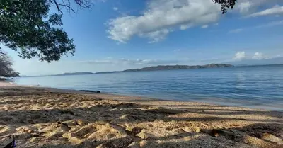 a beach with a view of the water at Casa Mangos Macondo Lepanto in Lepanto