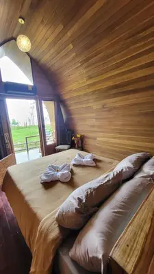 a large bed in a room with a wooden wall at Arenal 360 Lodge in Fortuna