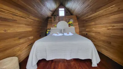 a bedroom with a white bed in a wooden wall at Arenal 360 Lodge in Fortuna