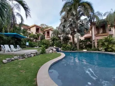 a swimming pool in front of a house with palm trees at Serena Suites H3 in Coco