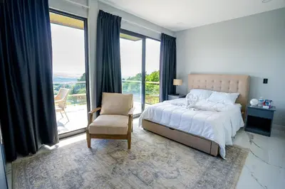 a bedroom with a bed and a chair and windows at La Parada House in Heredia