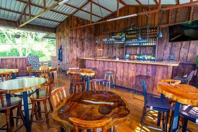 a restaurant with wooden tables and chairs and a bar at La Parada House in Heredia
