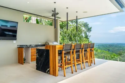 a kitchen with a bar with chairs and a view at Villa Serenidad in Uvita