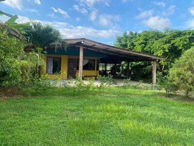 a small yellow house with a grass yard at Casa Vacacional fachento house in Parrita