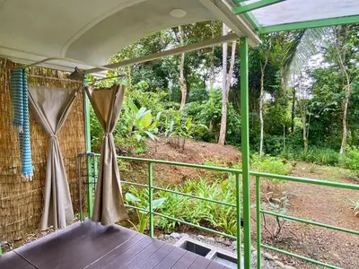 a screened in porch with a table and curtains at Jungle Bus, 5 min drive to PlayaLinda, 15 to Dominical, Wifi Starlink in Quepos