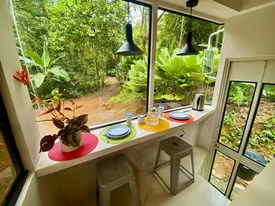 a room with a window with a table and chairs at Jungle Bus, 5 min drive to PlayaLinda, 15 to Dominical, Wifi Starlink in Quepos