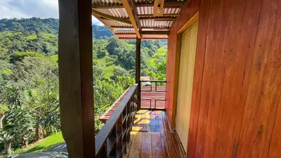 a wooden balcony of a house with a view of the mountains at Digrú Spaa in Pejibaye