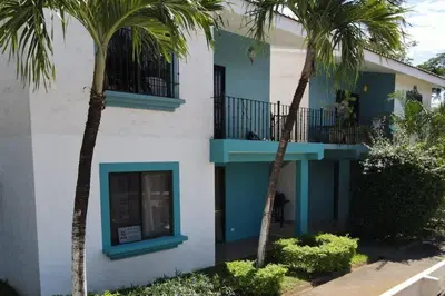 a building with palm trees in front of it at Minimalist Condo with a Beautiful New Design, Bound Patio, and Shared Community Pool in Coco